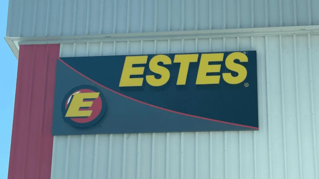 Exterior sign reading ESTES in large yellow letters on a dark blue panel with a red diagonal stripe and a circular E logo.