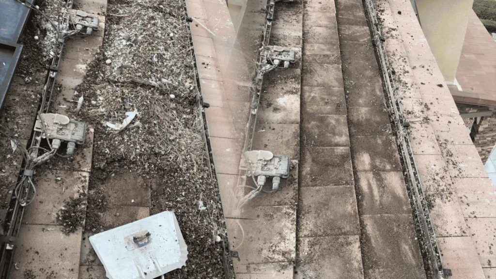Top‑down view of a dirty stairwell with debris, exposed cables, and electrical boxes along concrete steps.
