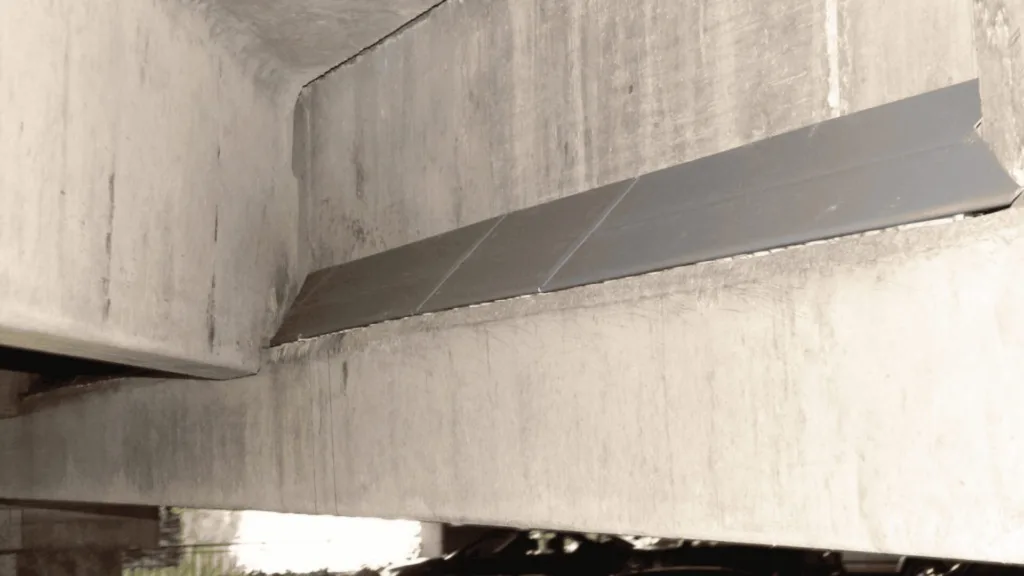 Concrete industrial ceiling with a diagonal metal brace running along a beam.