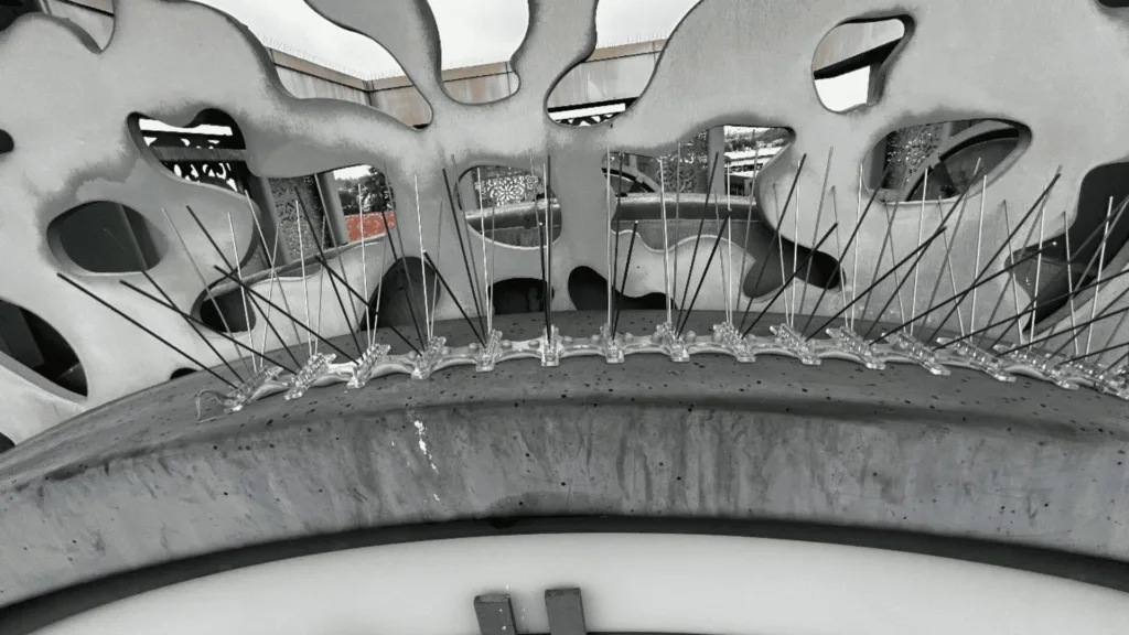 Close-up of a studded tire tread with metal studs protruding along the rim, in black-and-white tones.