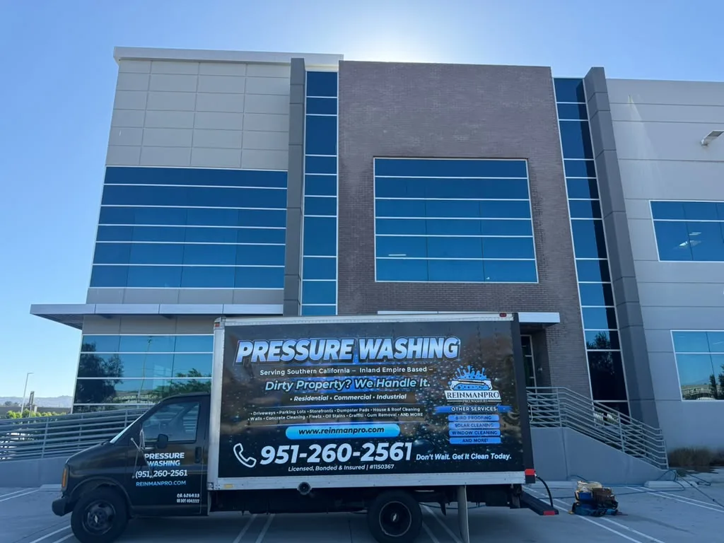 Commercial building with a pressure-washing truck parked in front, advertising 'Pressure Washing' on the side.