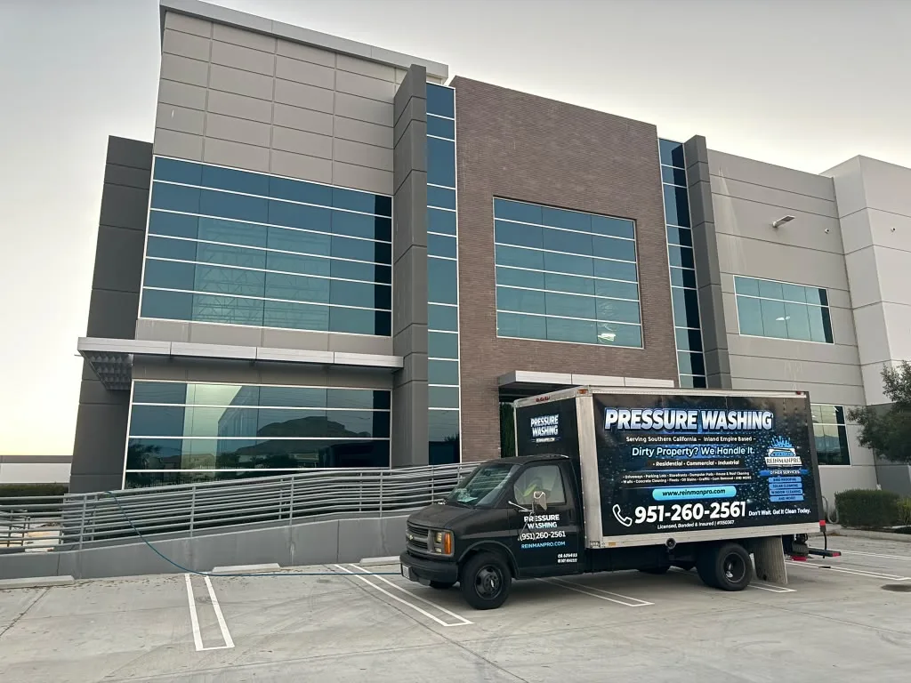 Modern office building with large glass windows and brick accent, parked truck labeled 'Pressure Washing' in foreground