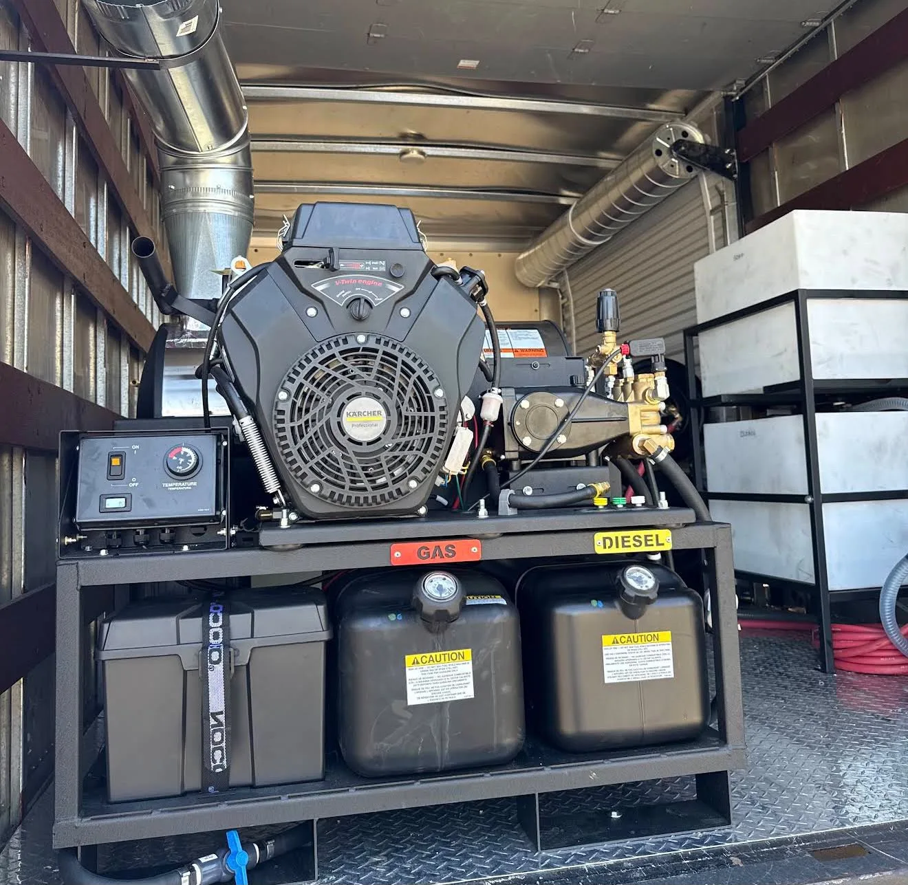 Portable generator set mounted on a metal frame inside a trailer, with labeled GAS and DIESEL tanks and fuel lines connected to hoses and gauges.