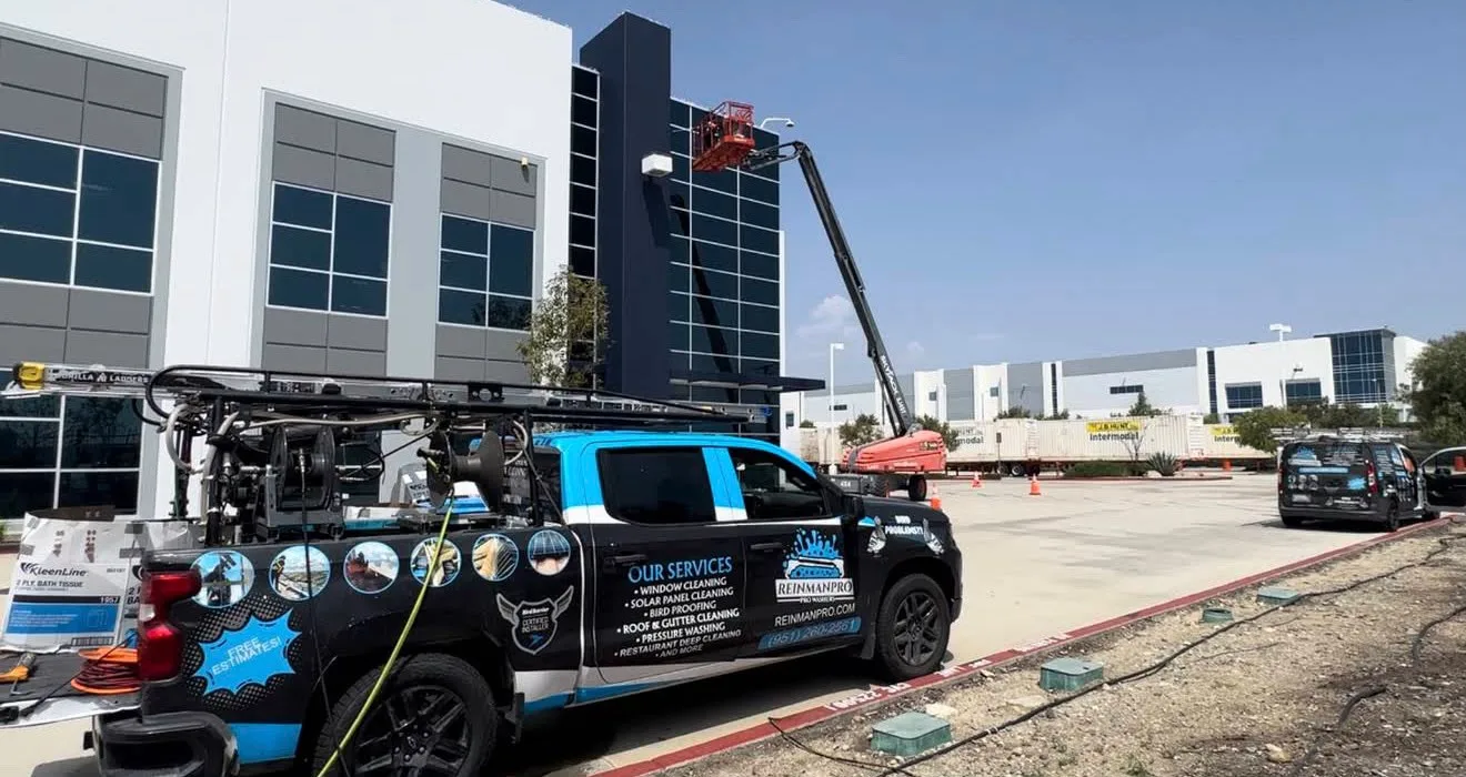 Service truck with a hydraulic boom cleaning windows on a modern office building exterior