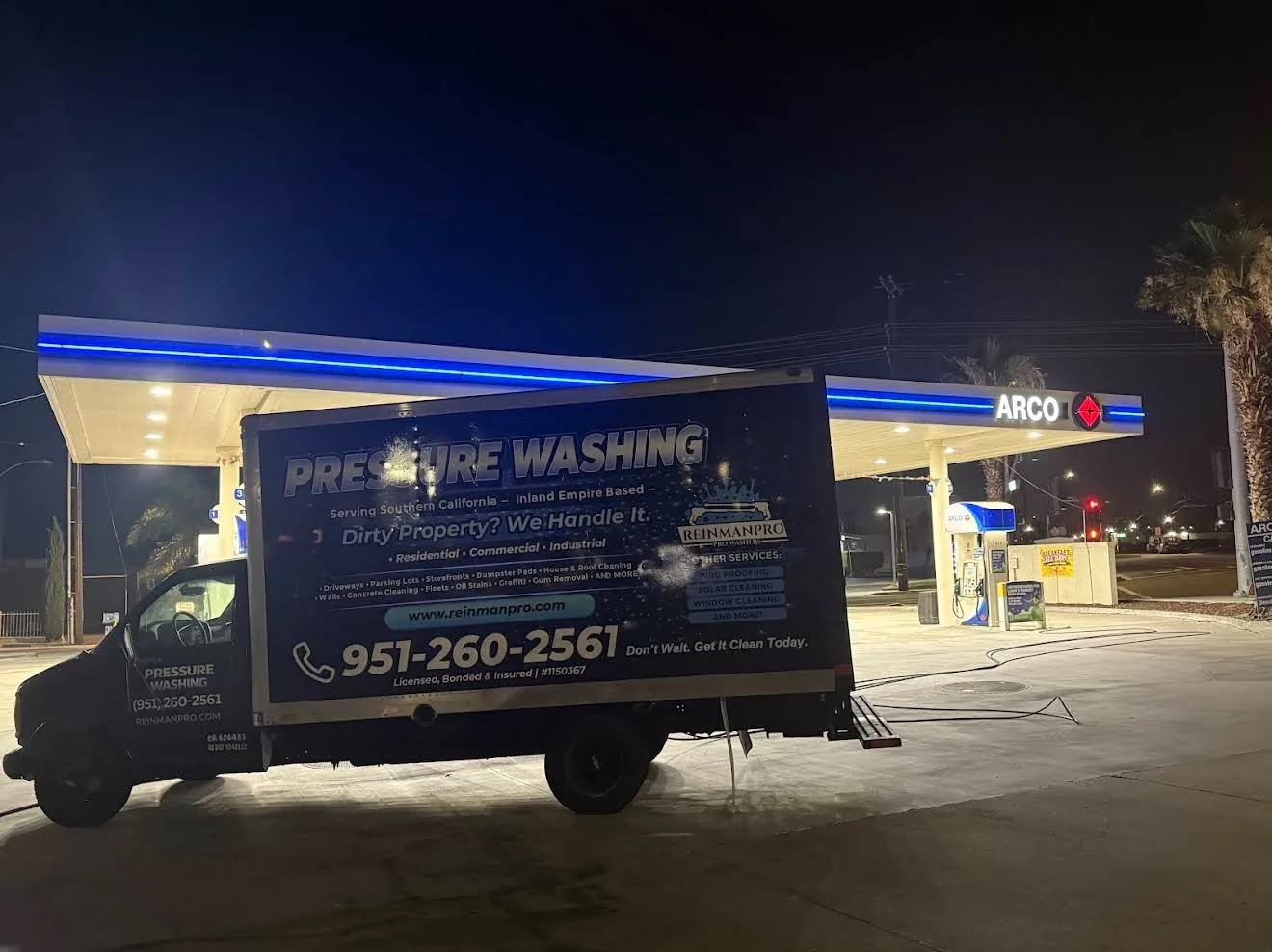 Nighttime at an ARCO gas station with a pressure-washing service truck parked in front; bold 'Pressure Washing' ad on the side of the truck.